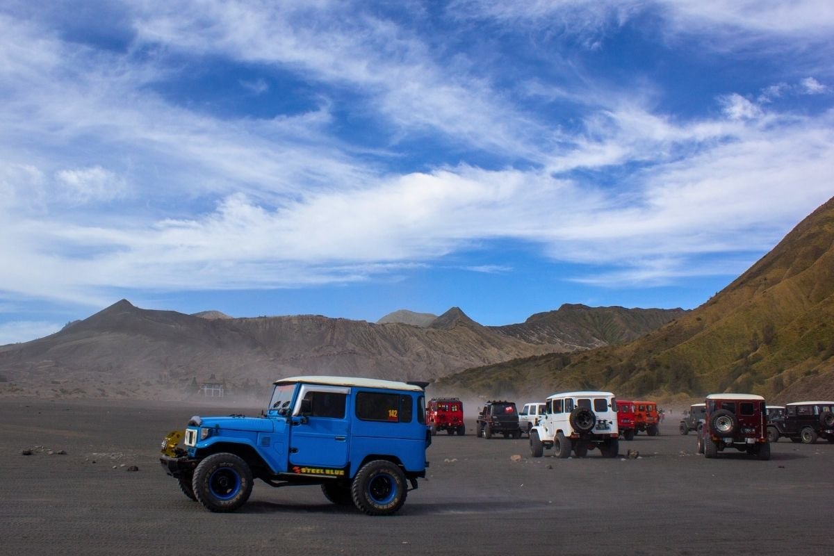 4WD jeep Bromo driving across the sea of sand inside the Mount Bromo caldera landscape